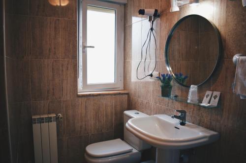 uma casa de banho com um WC, um lavatório e um espelho. em Hotel Brisas del Sella em Ribadesella