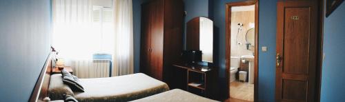 a bedroom with a bed and a bathroom with a mirror at Hotel Brisas del Sella in Ribadesella