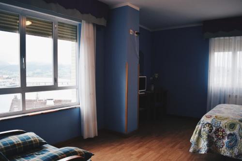 a blue room with a bed and two windows at Hotel Brisas del Sella in Ribadesella