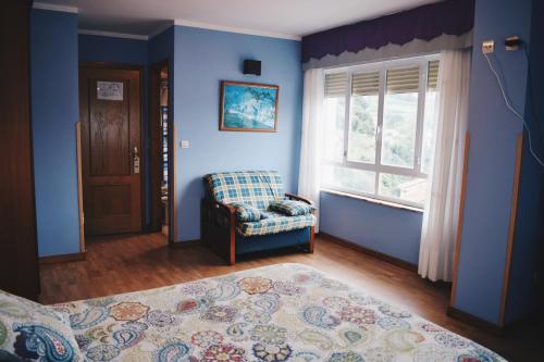 Habitación azul con silla y ventana en Hotel Brisas del Sella, en Ribadesella