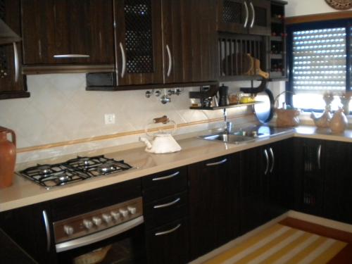 a kitchen with wooden cabinets and a stove top oven at Cantinho do Céu in Vila Real de Santo António