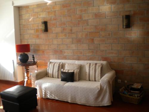 ヴィラ・レアル・デ・サント・アントニオにあるCantinho do Céuのレンガの壁の客室で、白いソファ(枕付)