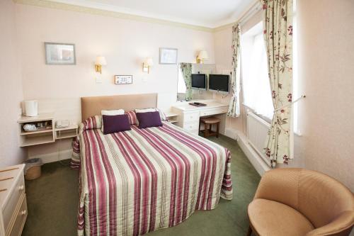 a hotel room with a bed and a desk and a window at Livermead House Hotel in Torquay