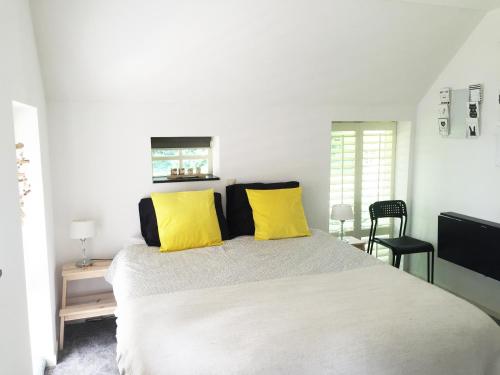 um quarto com uma cama grande e almofadas amarelas em B&B De Achterdiek em Ruinen