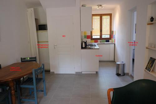 セーニョンにあるEnvies en Lubéronのテーブル付きの部屋、白いキャビネット付きのキッチンが備わる客室です。