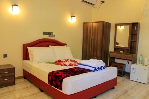 a bedroom with a large bed with a wooden headboard at Evila Inn - Thoddoo in Thoddoo