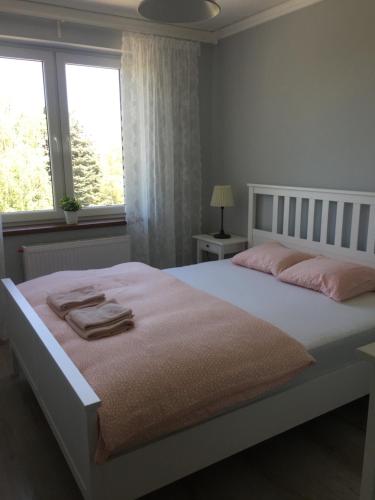 a bedroom with a white bed with pink towels on it at Apartament Antek klimatyzowany in Oświęcim