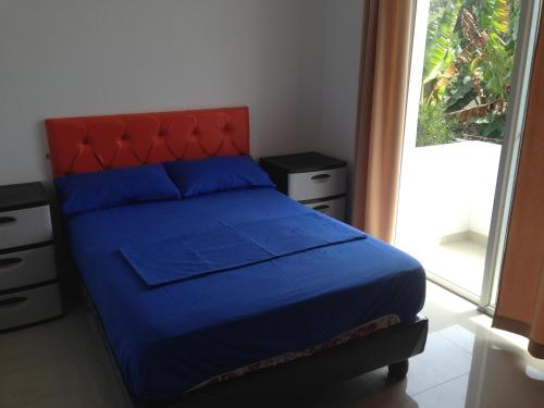 a bedroom with a blue bed with a red headboard and a window at Hotel Almond Beach in Tonsupa