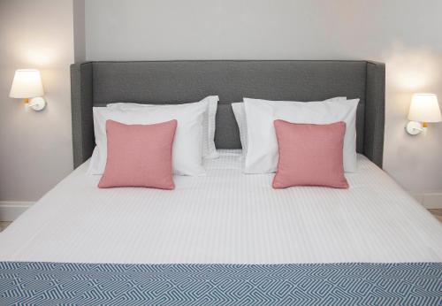 un grande letto con due cuscini rosa sopra di Aquarius Boutique Hotel a Rethymno