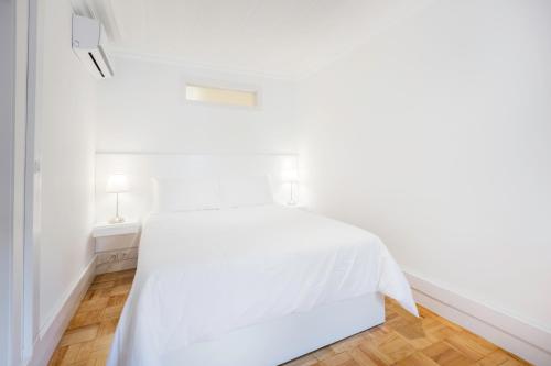 een wit bed in een witte slaapkamer met een houten vloer bij Your Place in Lisbon in Lissabon