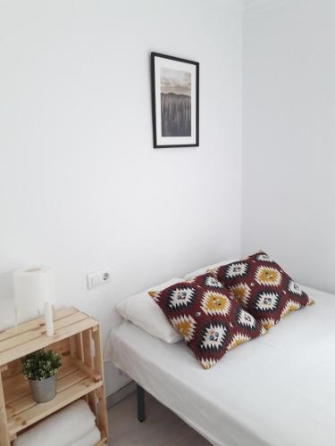 a bed with a pillow on it next to a table at CH II Apartments ZONA DE OCIO NOCTURNO in Conil de la Frontera