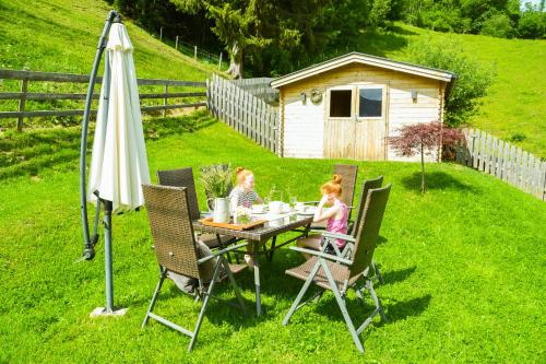 two children sitting at a table with an umbrella at Kendlhof in Sankt Johann im Pongau