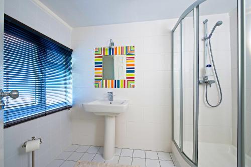 a white bathroom with a sink and a shower at Godalming Hotel Guest House in Godalming