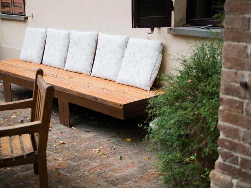 a wooden bench with four white pillows on it at La Luna nel Pozzo in Parma