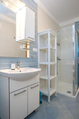 a white bathroom with a sink and a shower at Apartment Veve in Privlaka