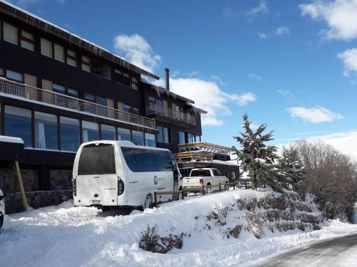 a van parked in the snow in front of a building at Hotel HF in Farellones