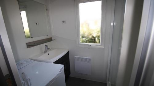une salle de bain blanche avec un lavabo et une fenêtre dans l'établissement Mobile Home - Camping, aux Mathes