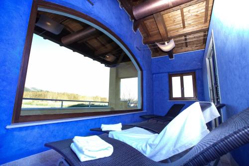Habitación azul con cama y ventana en La Dimora del Baco Hotel, en LʼAquila