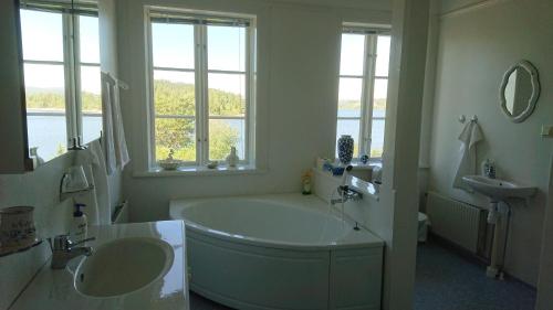 Baño blanco con bañera grande y lavamanos en Salsåker Herrgård, en Salsåker
