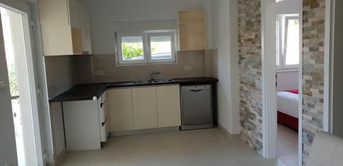 Elle comprend une petite cuisine avec un évier et une fenêtre. dans l'établissement Apartments Mia Bilo, à Podgreben