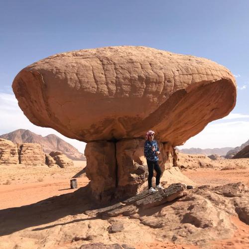 a person standing in front of a rock formation at RUM STARDUST lUXURY CAMP in Wadi Rum