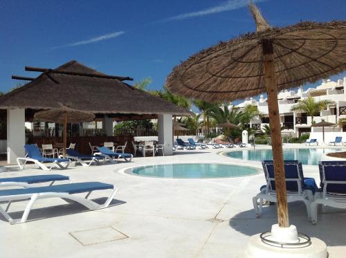 a resort with chairs and an umbrella and a pool at Adeje Paradise Apartments in Adeje