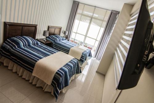 dwa łóżka w pokoju z oknem w obiekcie Apartamento Familiar Ideal w mieście Cochabamba