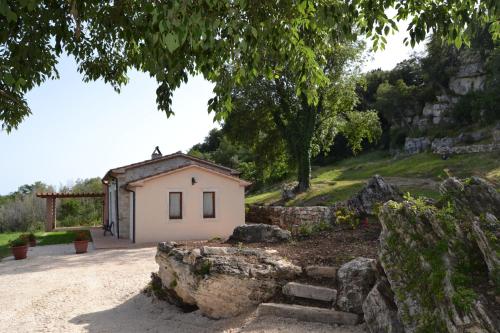 a small house with a stone wall next to a hill at Il Casale delle Mura in Saturnia