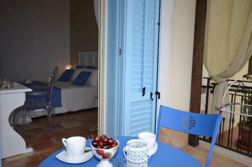 a blue table with a bowl of fruit and a bedroom at Catarin Comfort Rooms in Castelluzzo