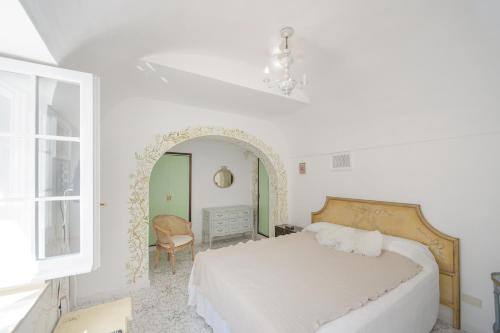 1 dormitorio blanco con 1 cama y 1 silla en Tragara 12C Art House, Capri en Capri