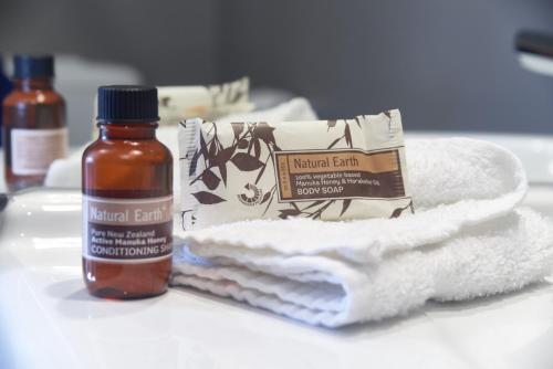 a bottle ofnatural earth essential oil next to towels and a bottle ofnatural earth at Salisbury Apartment - Christchurch Holiday Homes in Christchurch