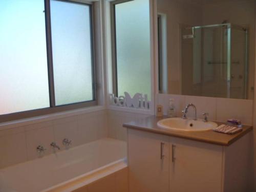a bathroom with a sink and a bath tub and a mirror at Cowes Holiday Haven - Property 1 in Cowes