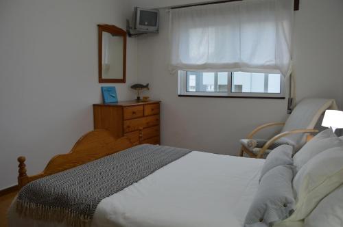 ポボア・デ・バルジンにあるApartamento Norton de Matosのベッドルーム1室(ベッド1台、椅子、窓付)