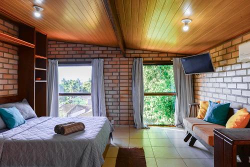 1 dormitorio con cama, sofá y ventanas en Adora Suites en Abraão