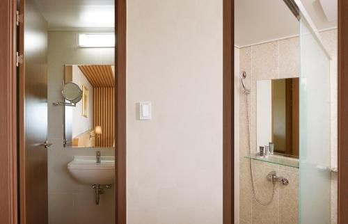 a bathroom with a sink and a toilet and a mirror at Jeju Aerospace Hotel in Seogwipo