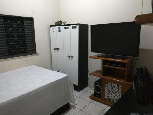 um quarto com uma cama e uma televisão e alguns armários em Casa em Fortaleza