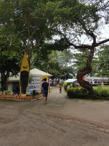 a man walking down a sidewalk next to a surfboard at Mactan Newtown Ocean View 360 Degree in Mactan