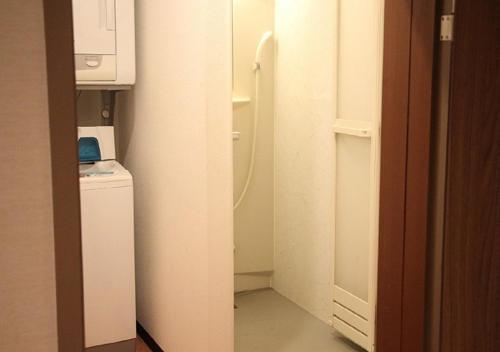 a small bathroom with a shower and a refrigerator at Fujikyu Unjokaku in Narusawa