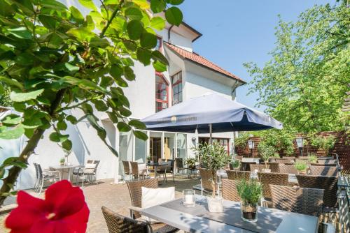 a patio with tables and chairs and an umbrella at Best Western Plus Hotel Am Schlossberg in Nürtingen