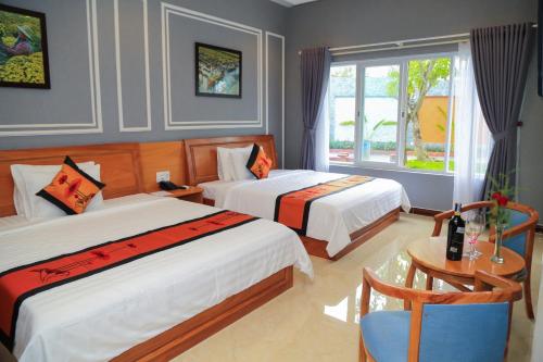 a bedroom with two beds and a table and a window at Van Kim Long in Ấp Ðông Quì