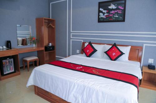 a bedroom with a large bed with red and white pillows at Van Kim Long in Ấp Ðông Quì