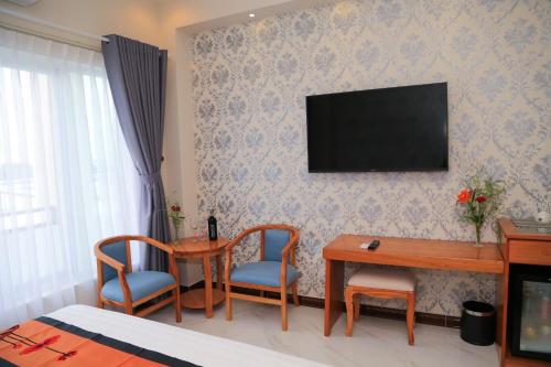 a hotel room with a desk and a television on a wall at Van Kim Long in Ấp Ðông Quì