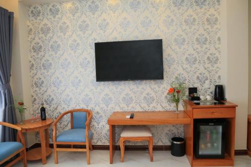 a living room with a table and a television on a wall at Van Kim Long in Ấp Ðông Quì