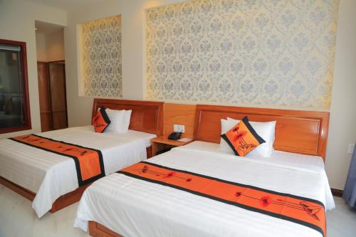 a bedroom with two beds with orange and white sheets at Van Kim Long in Ấp Ðông Quì