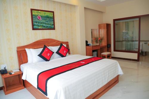 a bedroom with a large bed with red and black pillows at Van Kim Long in Ấp Ðông Quì