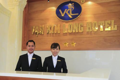 two people in suits standing in front of a sign at Van Kim Long in Ấp Ðông Quì