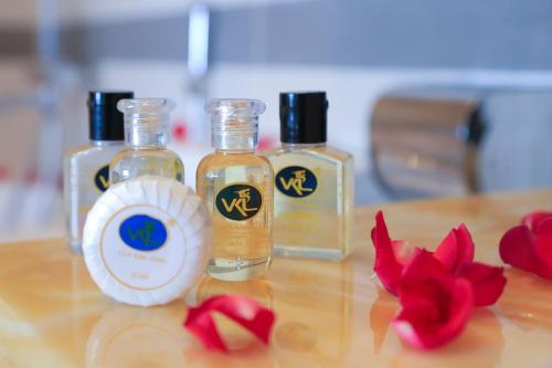 three bottles of essential oils on a table with red flowers at Van Kim Long in Ấp Ðông Quì