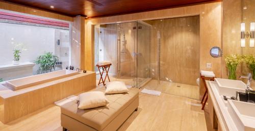 a bathroom with a couch and a tub and a sink at The Edge Bali in Uluwatu