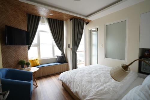a bedroom with a bed and a chair and a television at Homeland Hotel in Da Lat