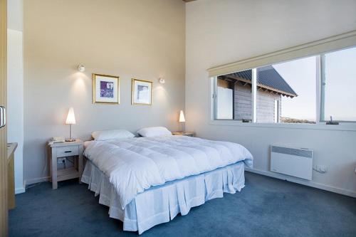 a white bedroom with a large bed and a window at White Crystal Apartments in Mount Hotham